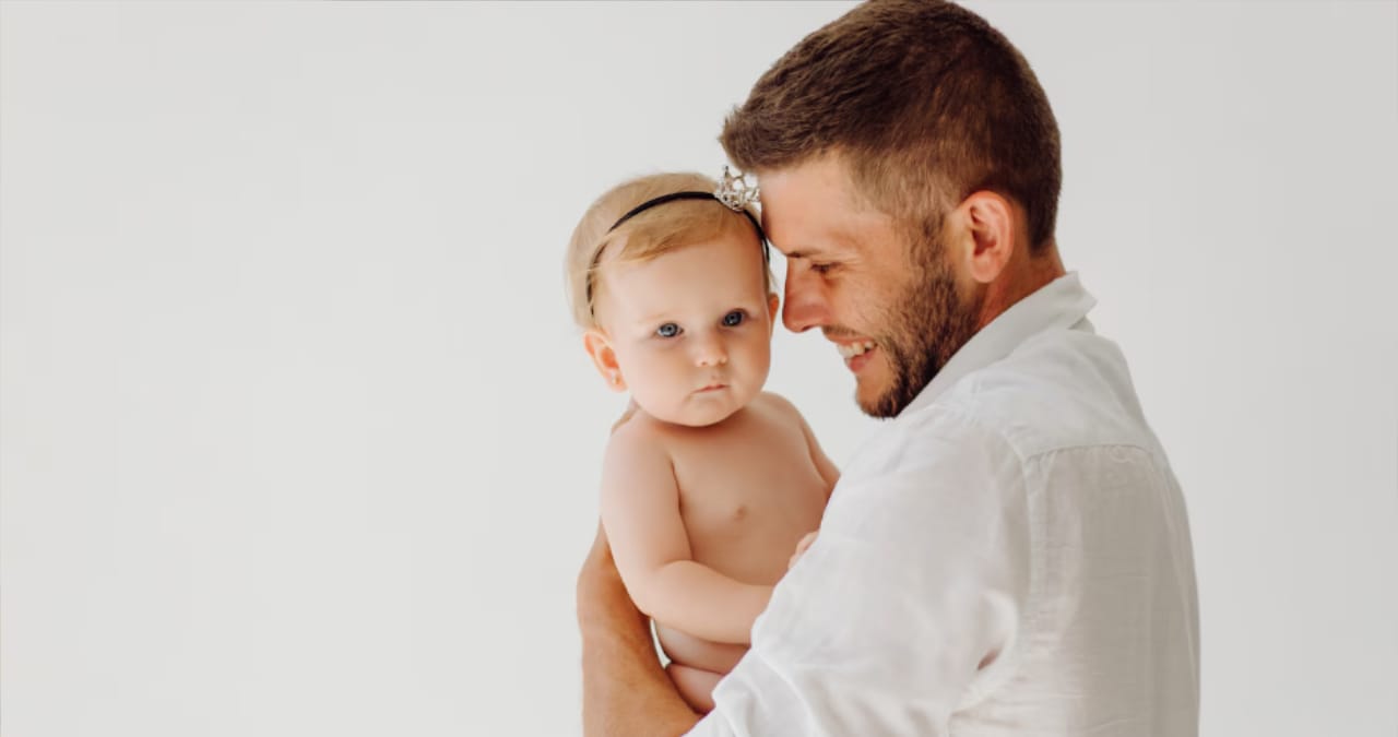 Tată fericit ținând bebelușul în brațe în perioada de concediu paternal plătit